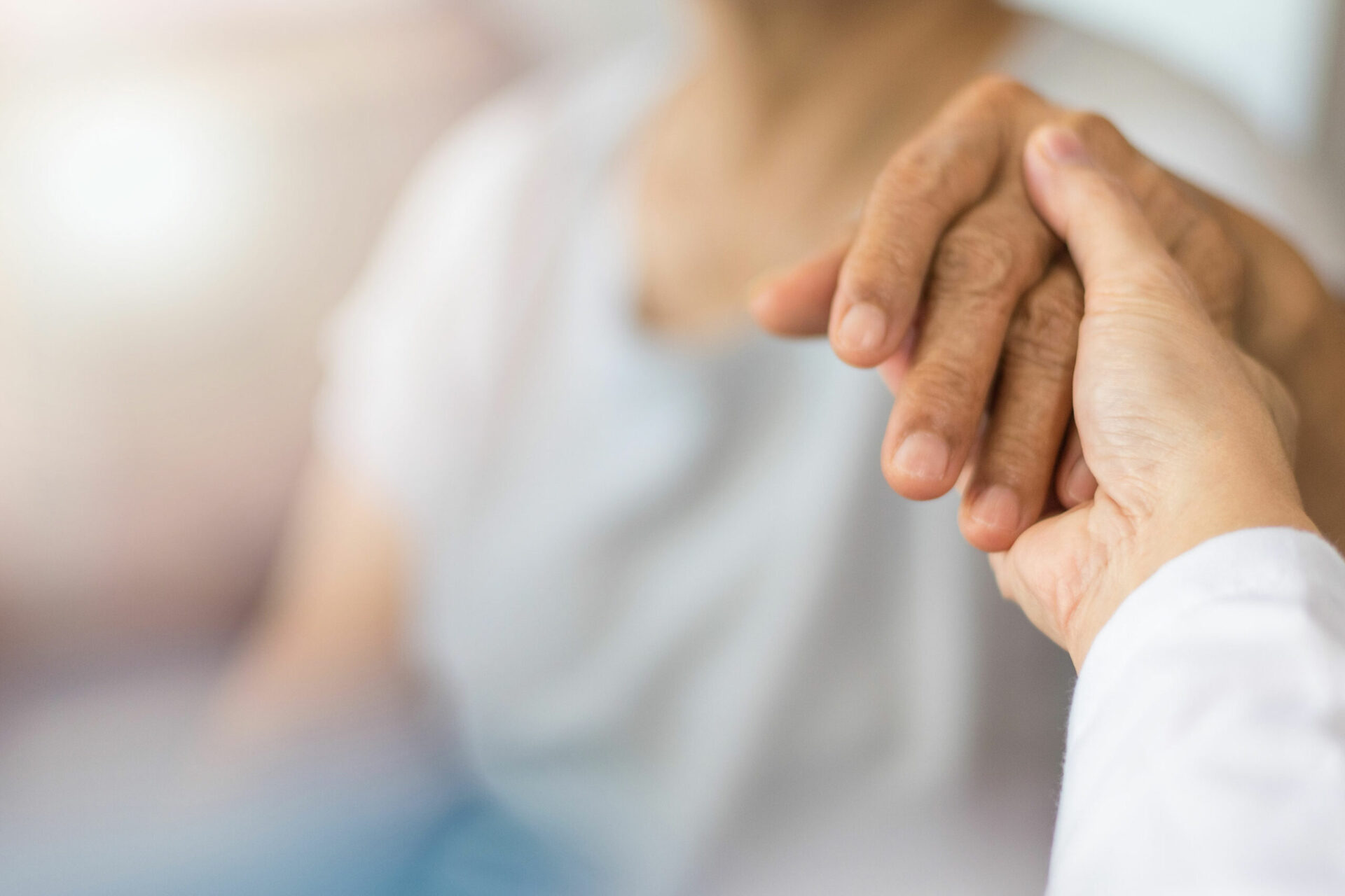 Ein Arzt legt seine Hand auf einen glücklichen älteren Patienten, um ihm Trost zu spenden – im Untersuchungszimmer eines Krankenhauses, in einem Hospiz, einem Pflegeheim oder einer Seniorenresidenz.